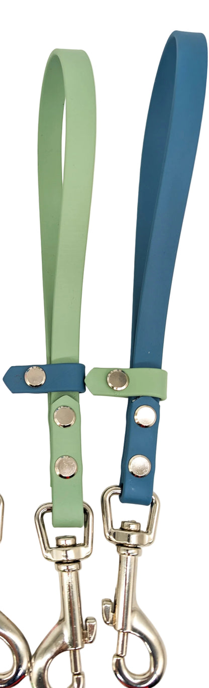 Two dog leashes with green and blue straps and metal clasps on a white background